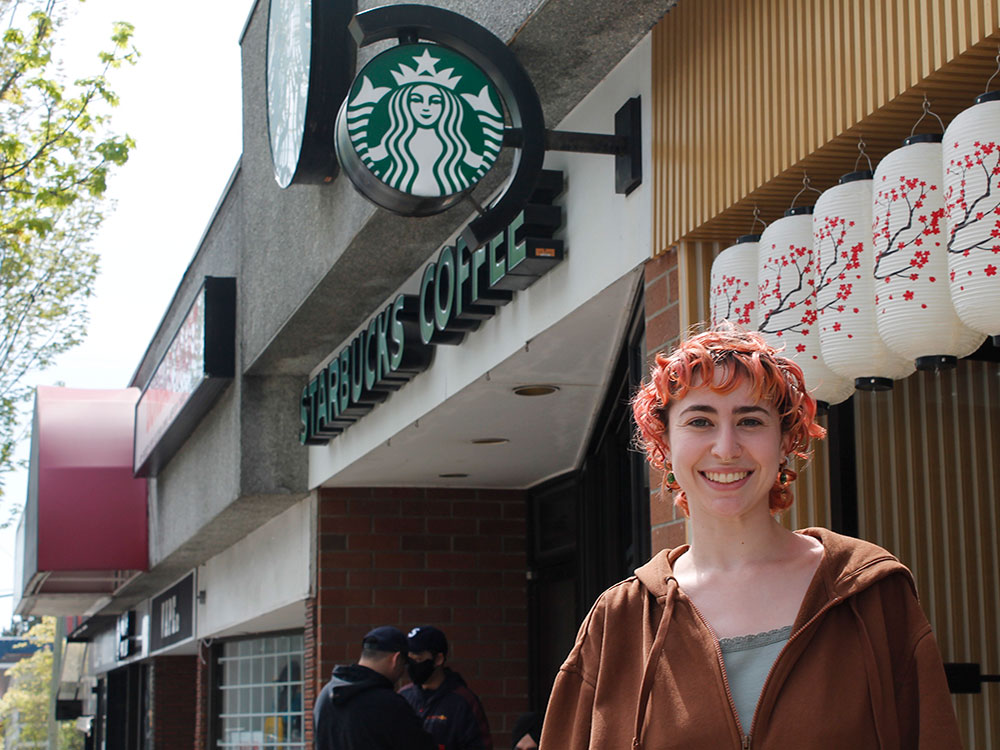 Frédérique Martineau, a woman in her 20s with short hair, smiles in front of a Starbucks.