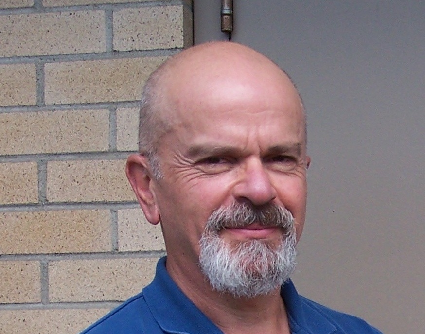 A headshot of a light-skinned, middle-aged man looking at the camera, wearing a blue polo shirt.