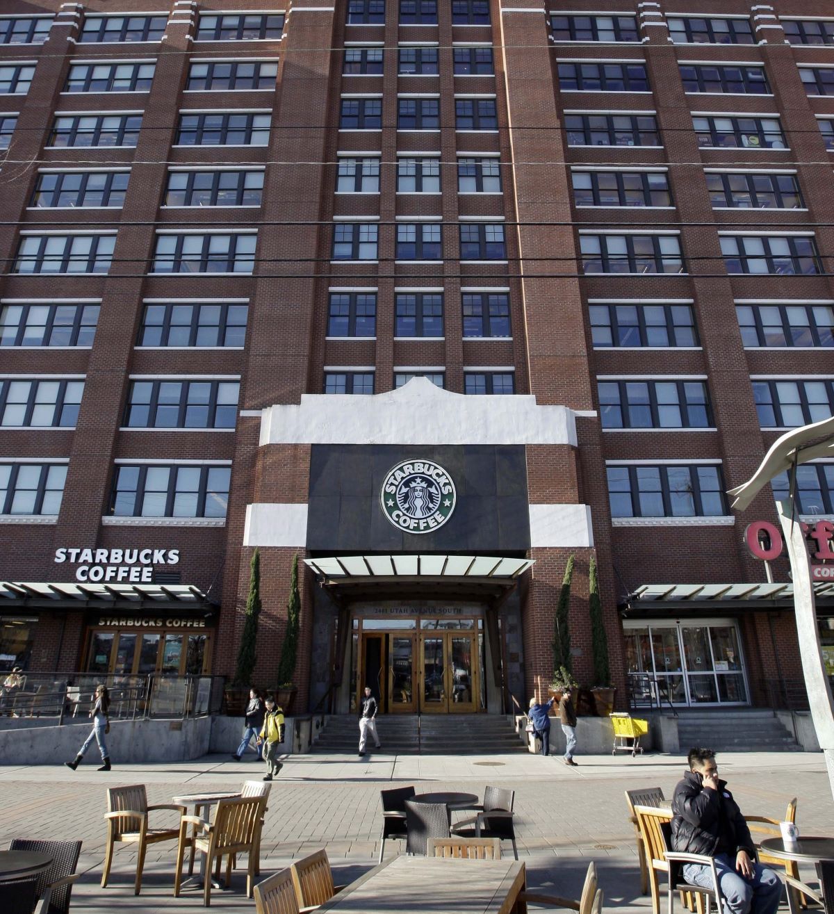 The facade of a brown brick building with rows of paned windows and the Starbucks Coffee logo above the front entrance.