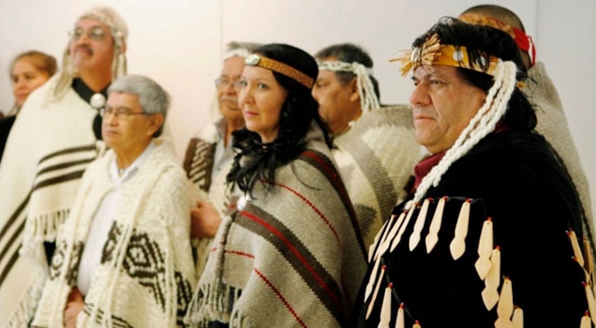 A younger Lydia Hwitsum stands among a group of Chiefs of the Hul’qumi’num Treaty Group, dressed in regalia.